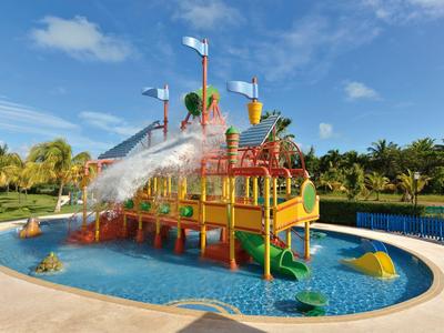 Parco giochi acquatico colorato con scivoli e fontane d'acqua in una piscina in una giornata di sole.