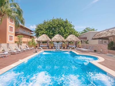 Area piscina esterna con lettini e palme in un resort alberghiero soleggiato.