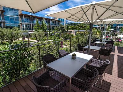 Moderner Außenbereich eines Hotels mit Tischen, Stühlen und großen Sonnenschirmen