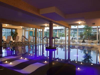 Moderner Indoor-Pool mit Lounge-Bereich und blauer Beleuchtung in einem Hotel.