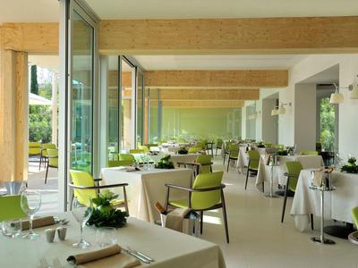 Hell eingerichteter Speisesaal mit großen Fenstern und grünen Stühlen in einem Hotel.