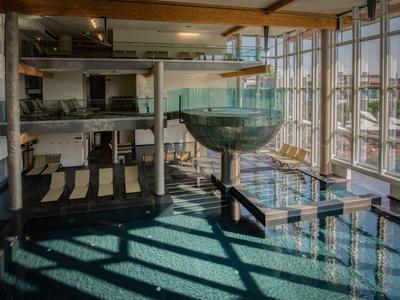 Moderner Innenpool mit Wasserfall und großen Glasfenstern in einem Hotel.