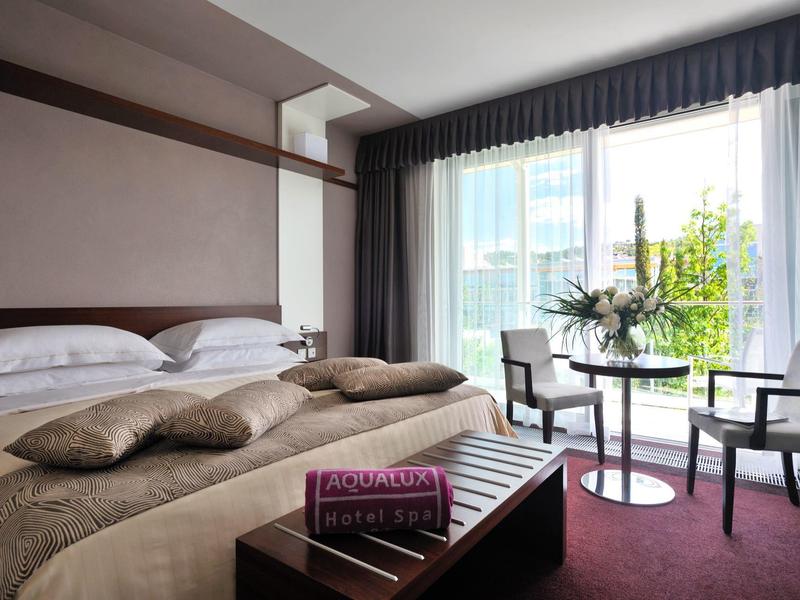 Modernes Hotelzimmer mit großem Bett, Sitzbereich und bodentiefen Fenstern mit Blick nach draußen