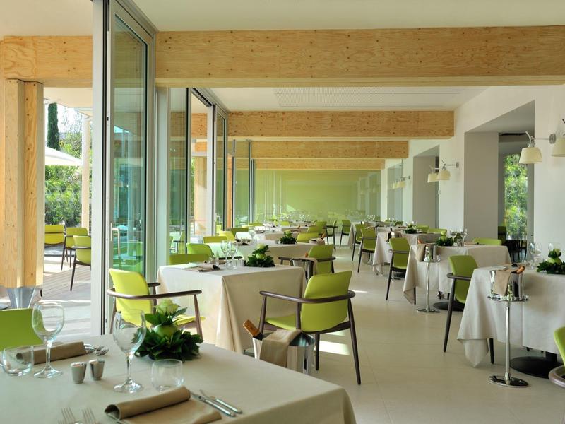 Hell eingerichteter Speisesaal mit großen Fenstern und grünen Stühlen in einem Hotel.