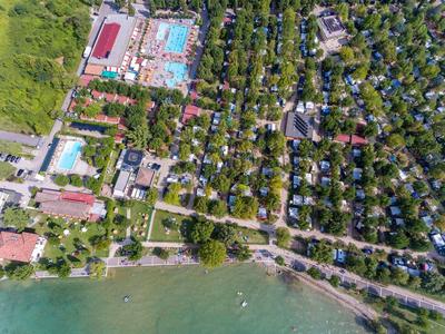 Aerial view of a campsite with many tents and cabins near a lake and several pools.
