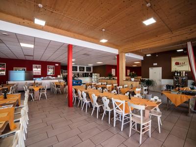 Großer, heller Speisesaal mit Holztischen und gemischten Stühlen in einem Hotel.