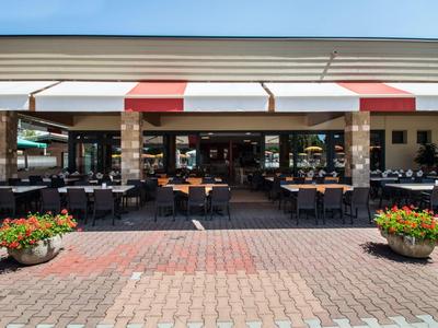 Outdoor seating area of a restaurant with tables, chairs, and sunshades
