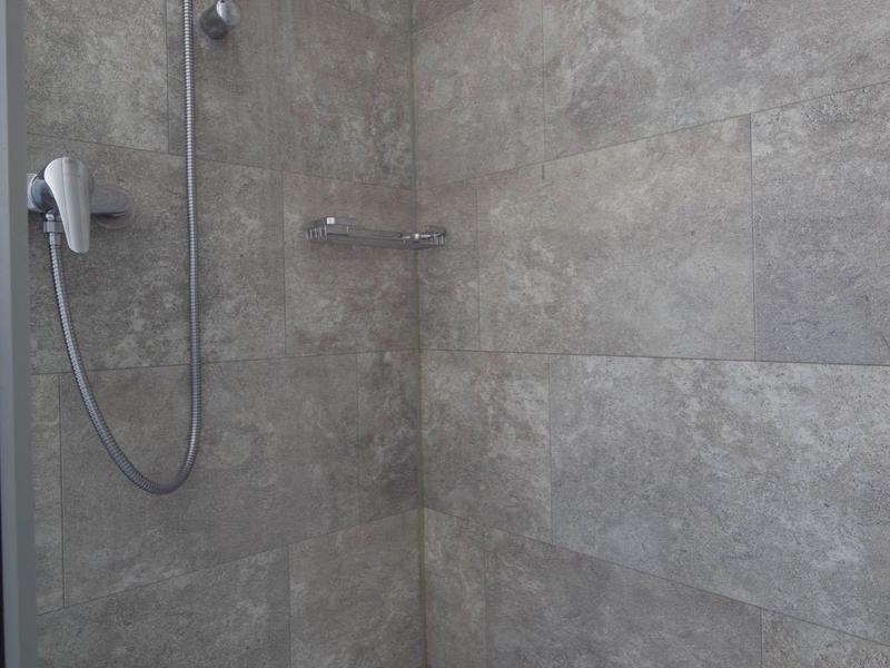 Aerial view of a resort with pools, sun terraces, and lush greenery near the water.