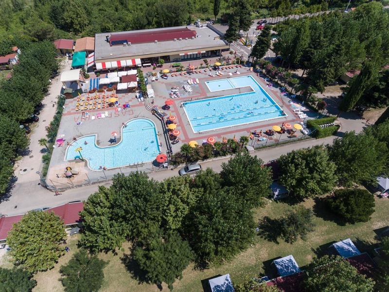 Aerial view of an outdoor pool with two large swimming pools and surrounding greenery.