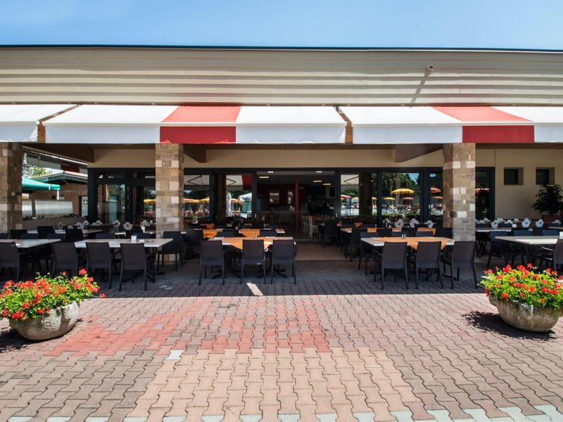 Outdoor seating area of a restaurant with tables, chairs, and sunshades