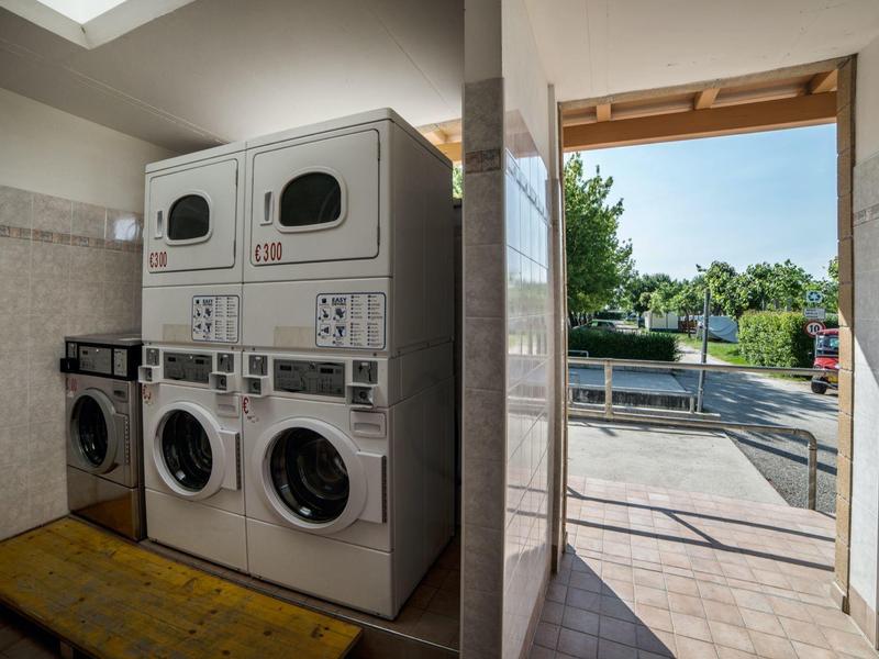 Washing machines and dryers in a bright, clean laundry area with access to the outdoors.