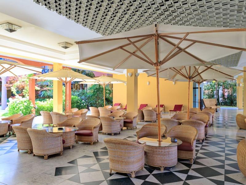 Ampio patio coperto con molte sedie e ombrelloni in un ambiente luminoso.