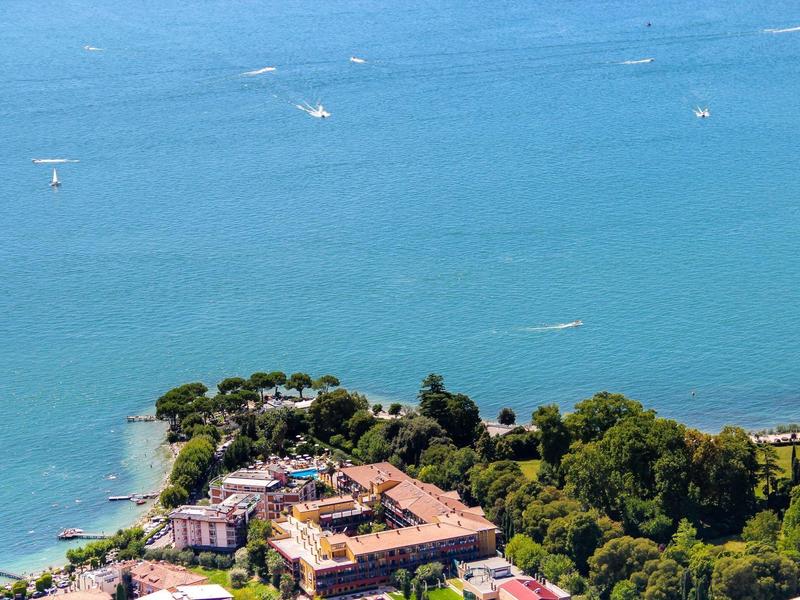 Isola con hotel e alberi verdi circondata da acqua blu con barche.