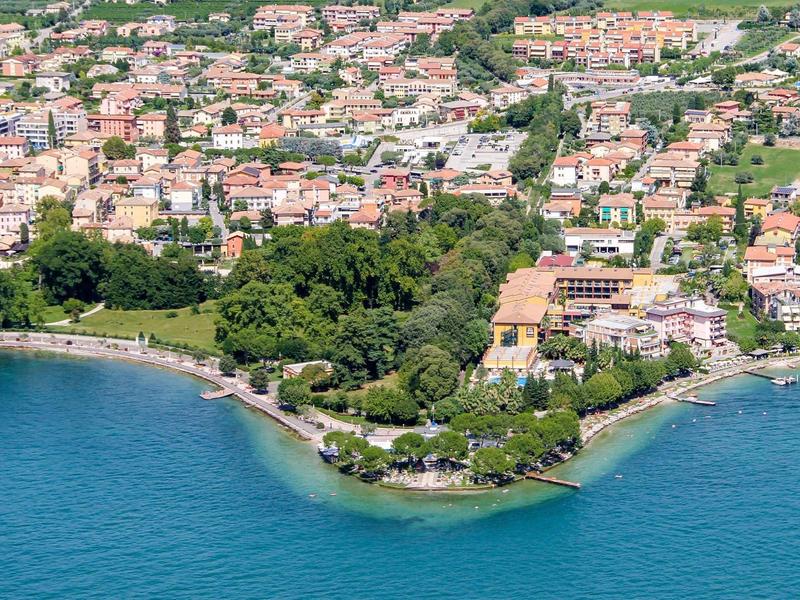 Vista aerea di una città costiera con spiaggia, alberi verdi e numerosi edifici