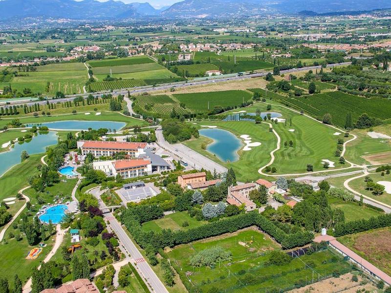 Luchtfoto van een resort met zwembaden, groene gebieden en paden in een landelijke omgeving.