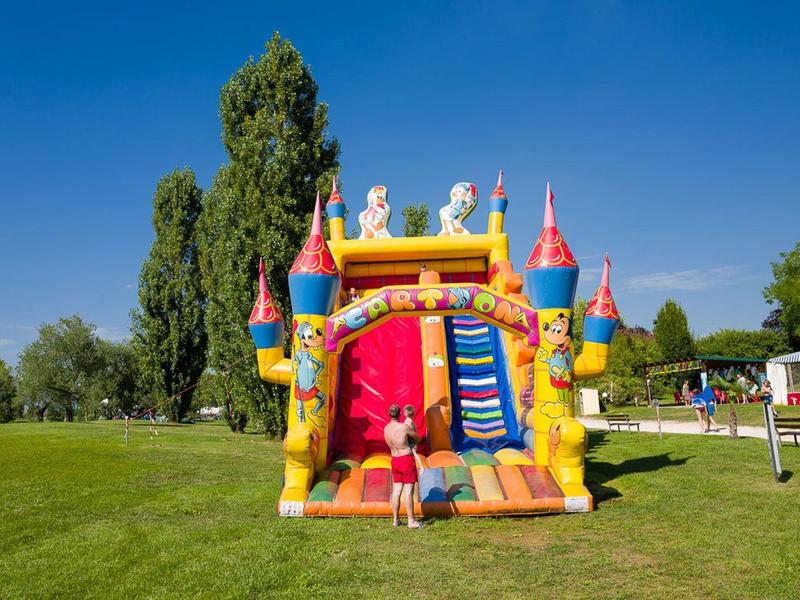 Kleurrijk opblaasbaar kasteel met kinderen op groen gras onder een blauwe lucht