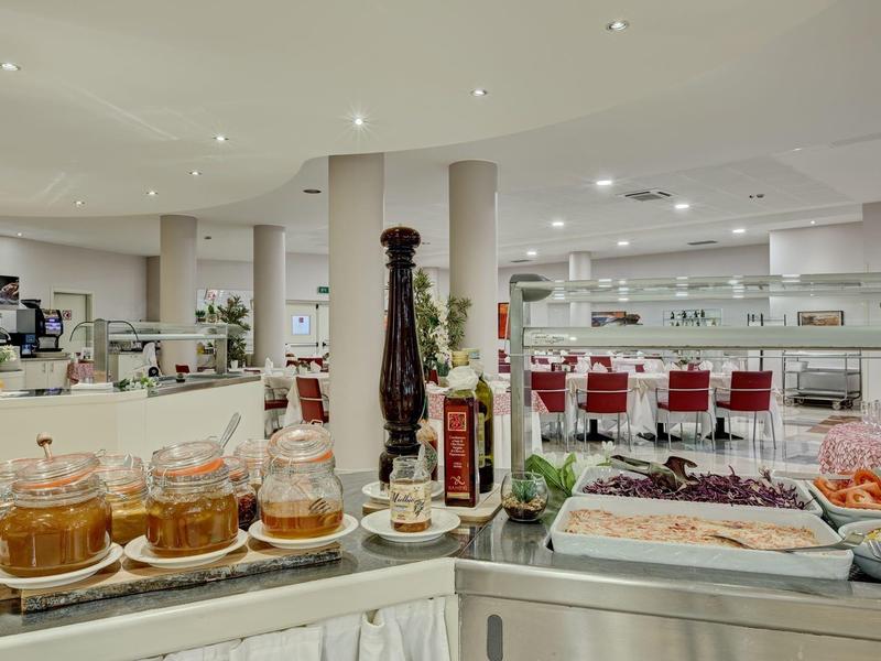 Helder verlichte ontbijtruimte in hotel met jam en buffetopstelling.