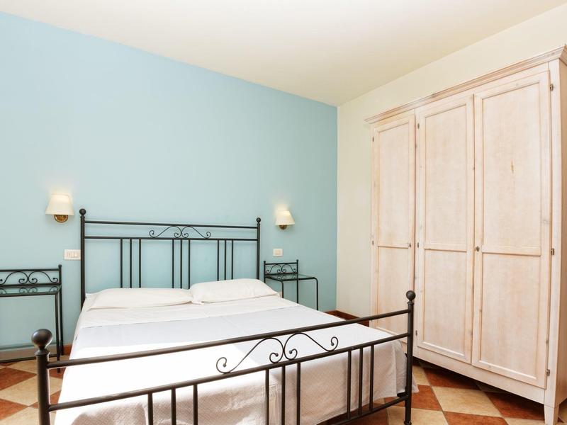 Slaapkamer met metalen bed, blauw geschilderde muur en witte kledingkast.