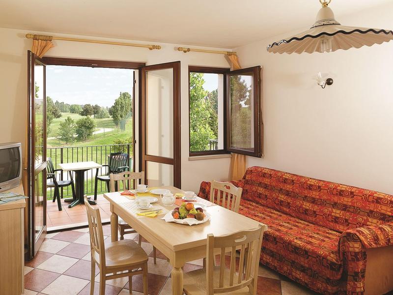 Gezellige eetkamer met bank en tafel, uitzicht op terras en groen landschap.