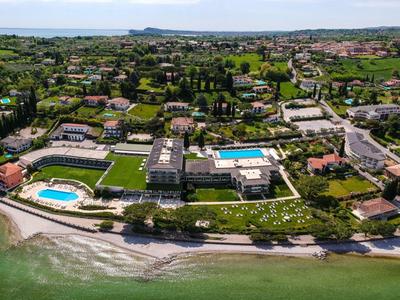 Küstenresort mit grünen Gärten, mehreren Pools und Sandstrand entlang des klaren blauen Meers.