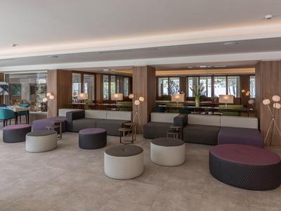 Moderner Hotel-Loungebereich mit runden Poufs und breiten Spiegeln an der Wand.