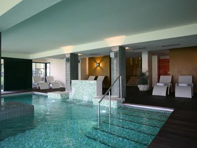 Innenraum eines modernen Wellnessbereichs mit beleuchtetem Pool, Liegestühlen und ruhiger Atmosphäre.