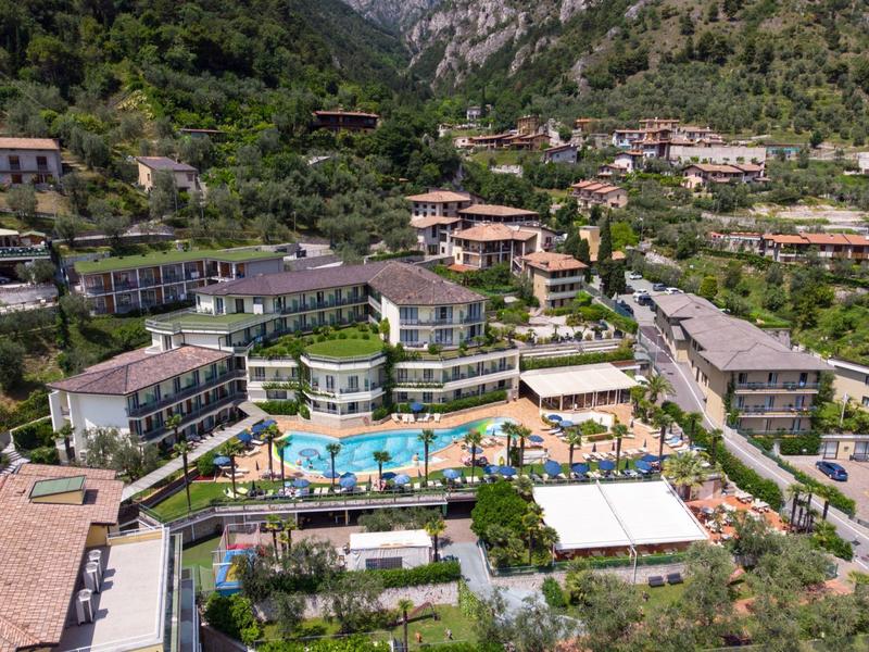 Hotel complex with multiple buildings, swimming pool, and surrounding green mountain landscape