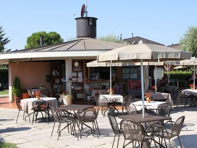Sunny outdoor café terrace with tables, chairs, and parasols.