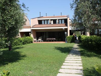 Modern bungalow with terrace and garden, surrounded by trees and a stone path.