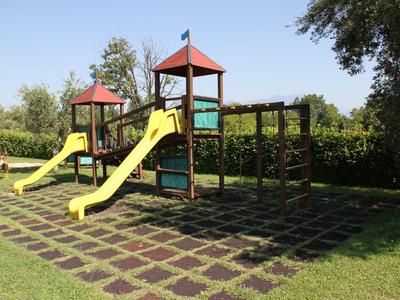 Playground with two yellow slides and climbing frame on grass under sunny sky.