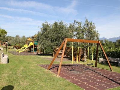 Playground with swings, slides, and climbing frames on grassy area under blue sky.