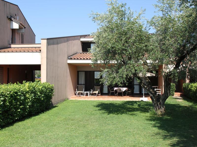 House with terrace and green garden under blue sky