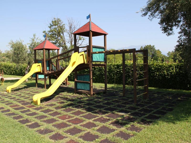 Playground with two yellow slides and climbing frame on grass under sunny sky.