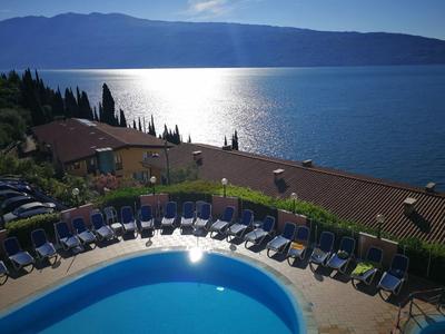 Piscina con tumbonas junto a un lago y montañas al fondo con cielo despejado.