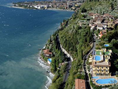 Paisaje costero con hoteles y piscinas junto al mar azul claro bajo un cielo nublado.