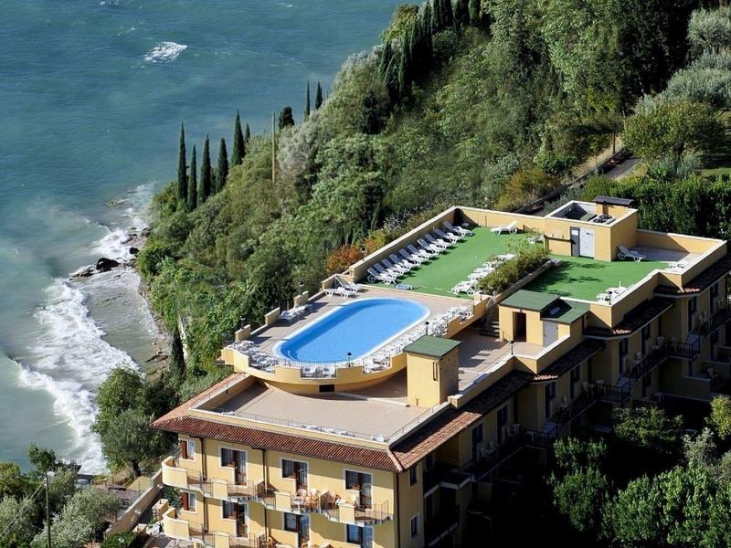 Hotel en la ladera con dos piscinas y vista al mar en un entorno verde.