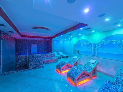 Interiér saunové oblasti s osvětlenými lehátky a dekorativními nástěnnými malbami.