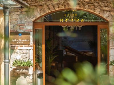 Wejście do hotelu z kamienną ścianą, drewnianymi drzwiami i roślinami