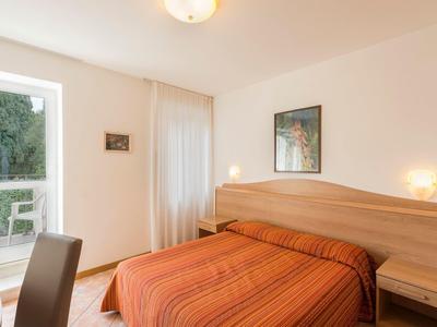 Jasny pokój z podwójnym łóżkiem i wyjściem na balkon z widokiem na zieleń.