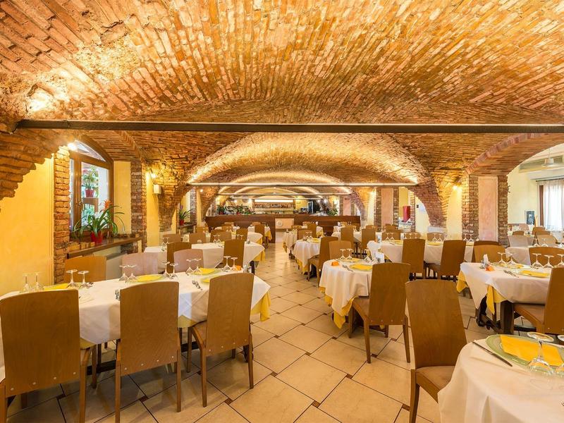 Elegancka jadalnia z sklepionym ceglastym sufitem i nakrytymi stołami w hotelu.