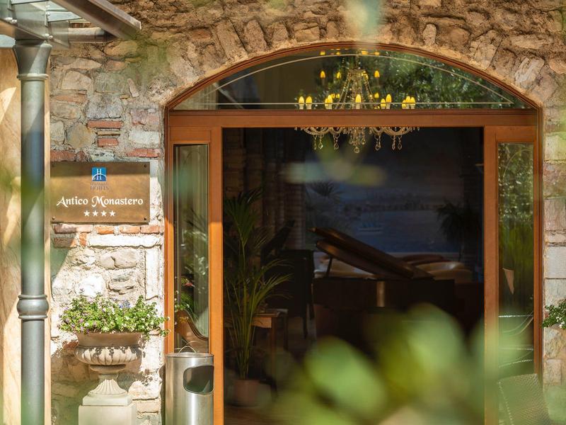 Wejście do hotelu z kamienną ścianą, drewnianymi drzwiami i roślinami