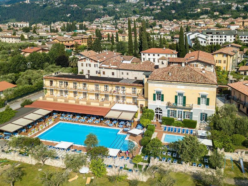 Ośrodek hotelowy z dużym basenem na zewnątrz, leżakami i widokiem na okoliczne miasto i wzgórza.