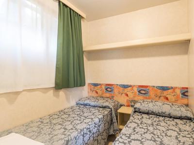 Habitación de hotel pequeña con dos camas individuales, colchas azules estampadas y cortina verde.