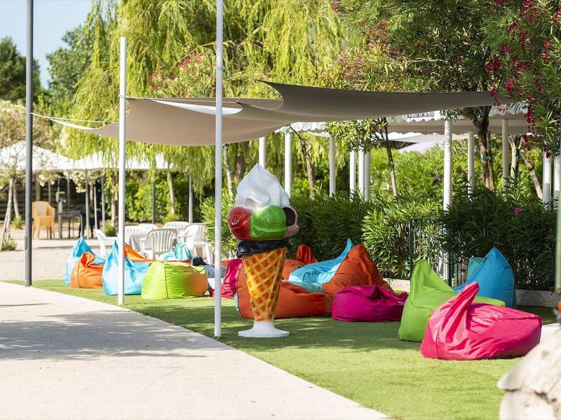 Área exterior con asientos coloridos y decoración de cono de helado en un entorno de hotel al aire libre.