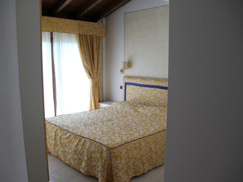 Classically furnished bedroom with patterned bedspread and curtains in warm tones.