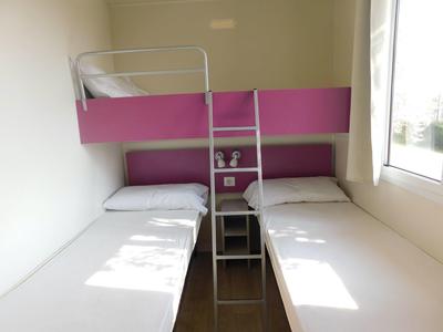 Kleines Zimmer mit zwei Einzelbetten, Etagenbett, Leiter und Fenster rechts, weiße Wände.