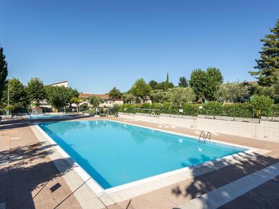 Ein großer rechteckiger Außenpool mit klarem Wasser, umgeben von Bäumen und blauem Himmel.