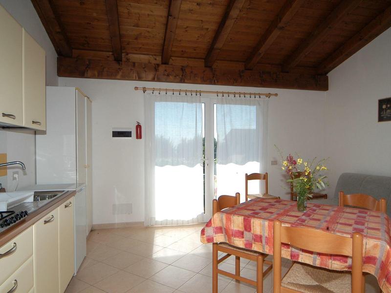 Heller Küchen- und Essbereich mit Holztisch, kariertem Tischtuch, Holzdecke und großem Fenster.