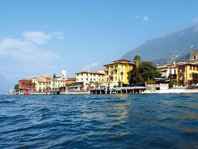 Vista di una città sul lago con edifici e montagne sullo sfondo.