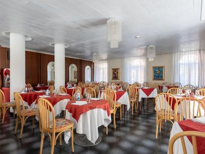 Brightly designed dining room with round tables and red tablecloths in a hotel.